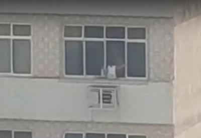 Criança é colocada em parapeito de janela de prédio