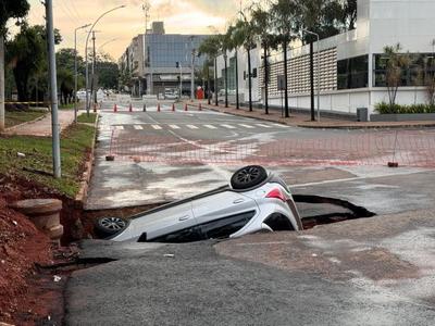 Carro é “engolido” por buraco após asfalto ceder durante chuva em Brasília