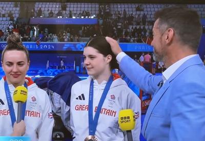 Pai comentarista faz carinho em filha medalhista olímpica durante entrevista ao vivo