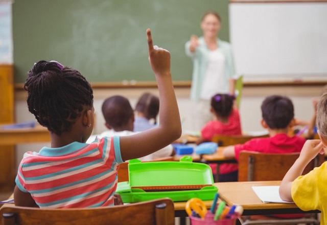 Professora aponta para aluna criança que está com a mão erguida (Reprodução/Educa Mais Brasil)