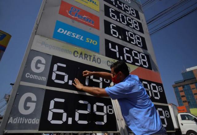 Funcionário troca placa de preço em posto de combustível