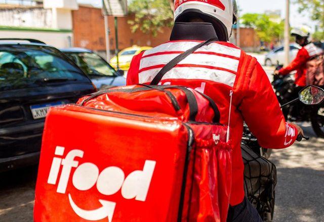 motoqueiro de entrega com uma mochila do aplicativo ifood em uma rua de cidade