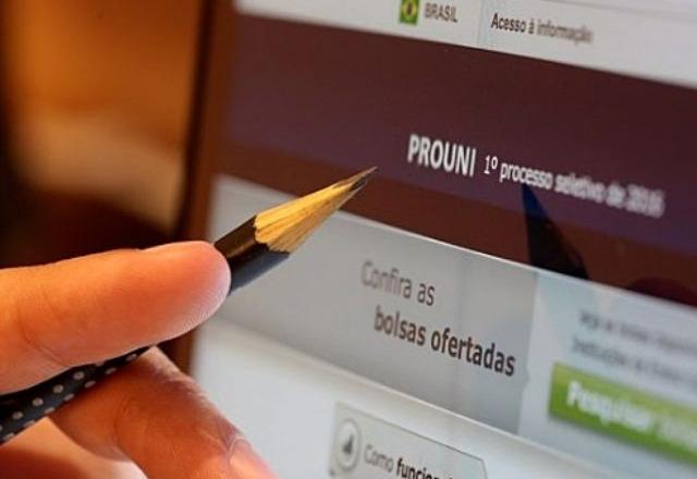 uma mão com lapis apontando para o site do prouni